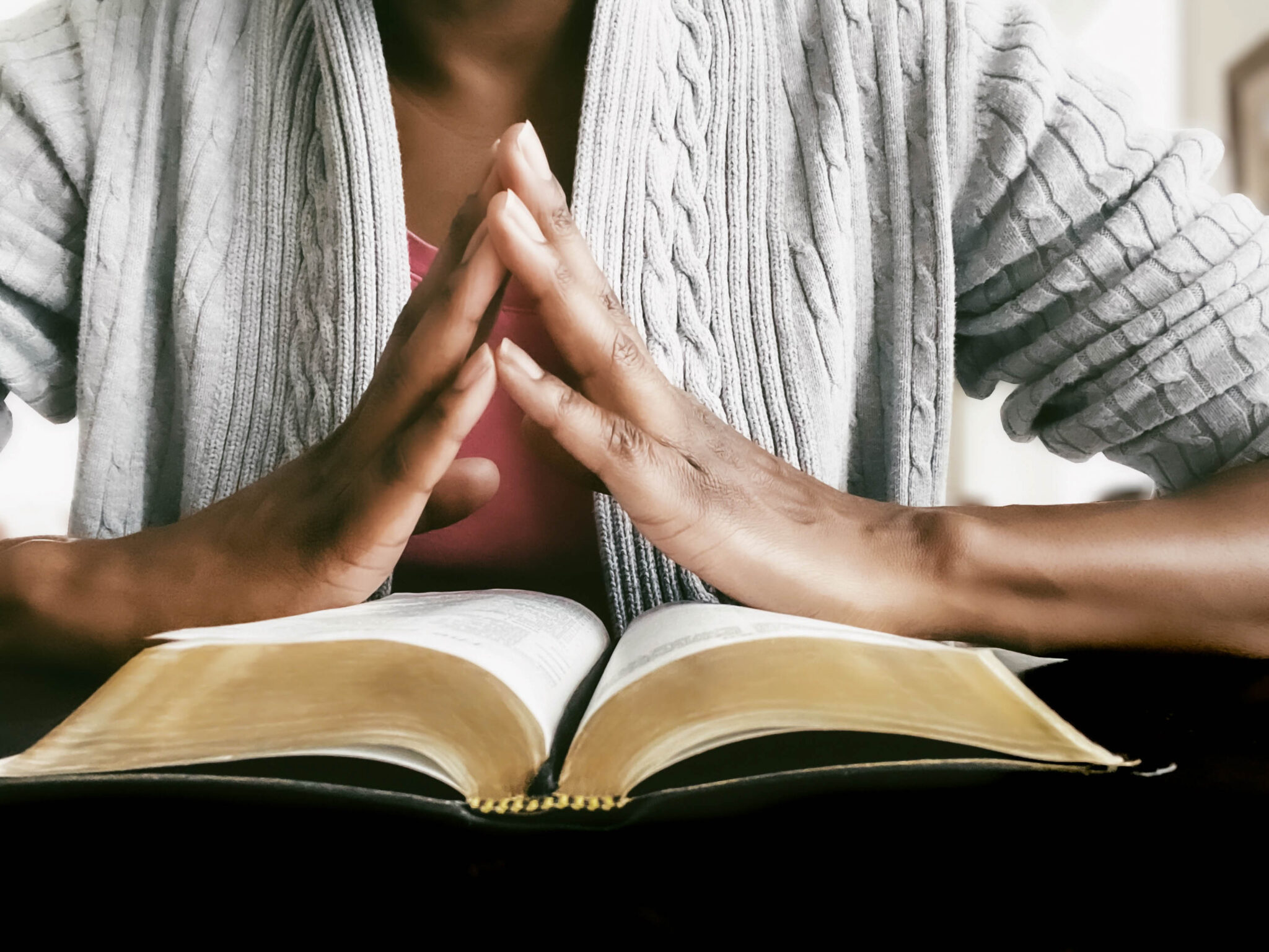 folded hands over bible