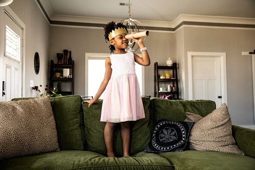 young girl wearing a crown standing on couch
