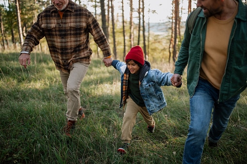 boy holding dad and grandpa's hands on hike