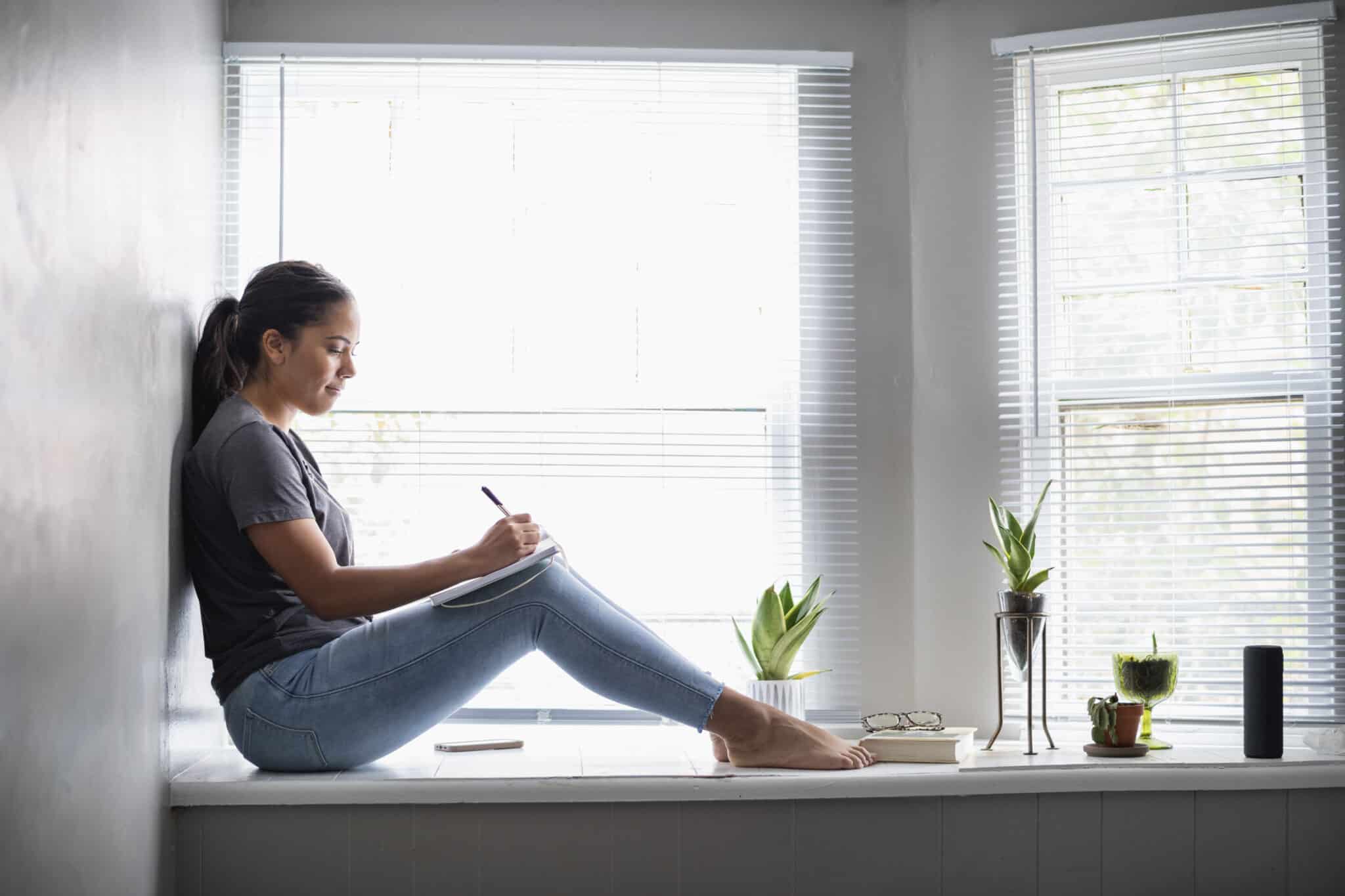 Woman sitting in widow seat writing
