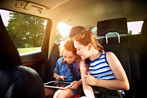 two girls looking at a tablet in the car