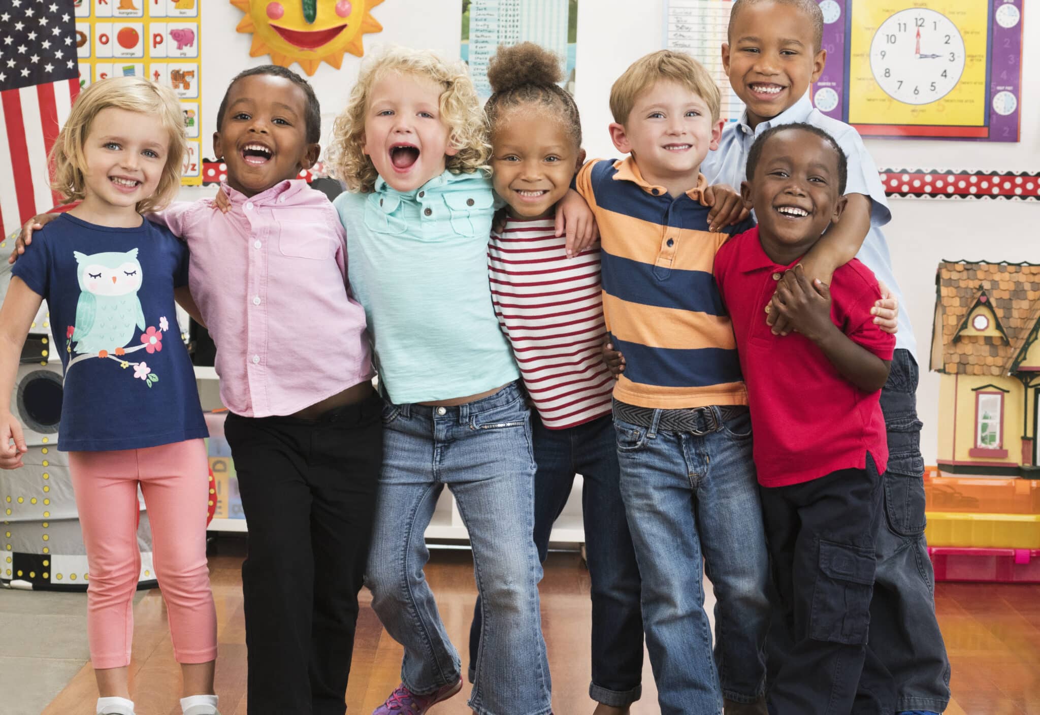 Portrait of smiling students hugging in a line in a classroom