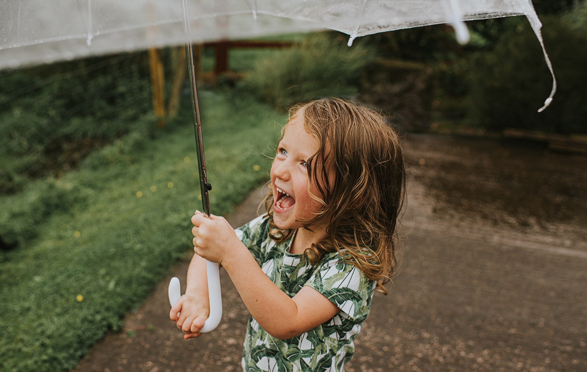 Joyful young child holding an Umbrella in the Rain