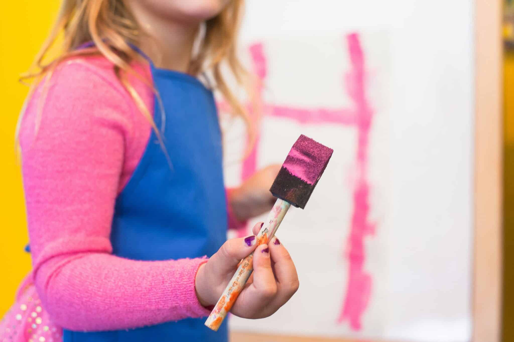 girl holding paintbrush with pink paint